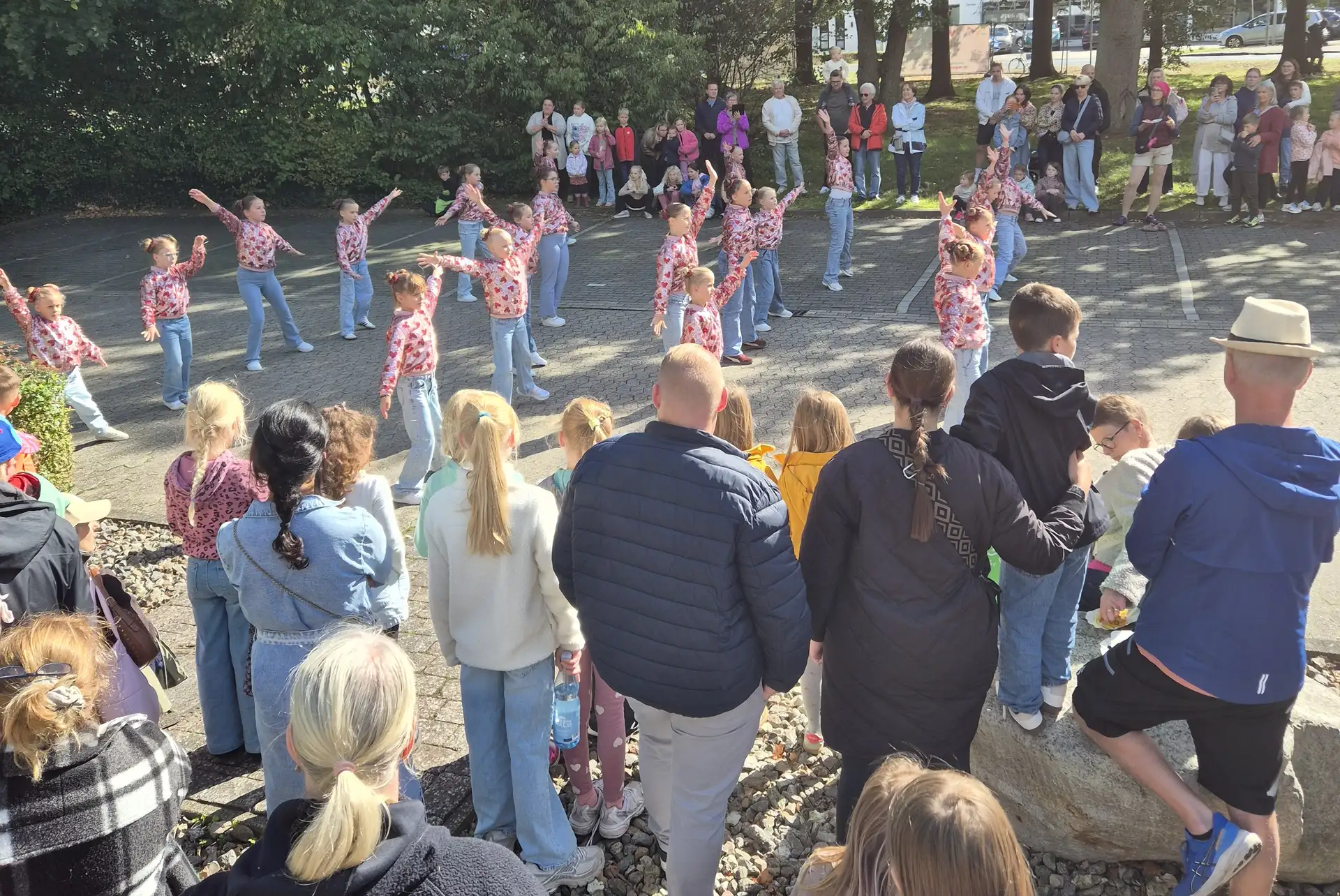 Tanzgruppe von Mädchen mit rosafarbenen Glitzerjacken bei einem Auftritt vor Zuschauern beim Weltkindertag im Rathauspark.