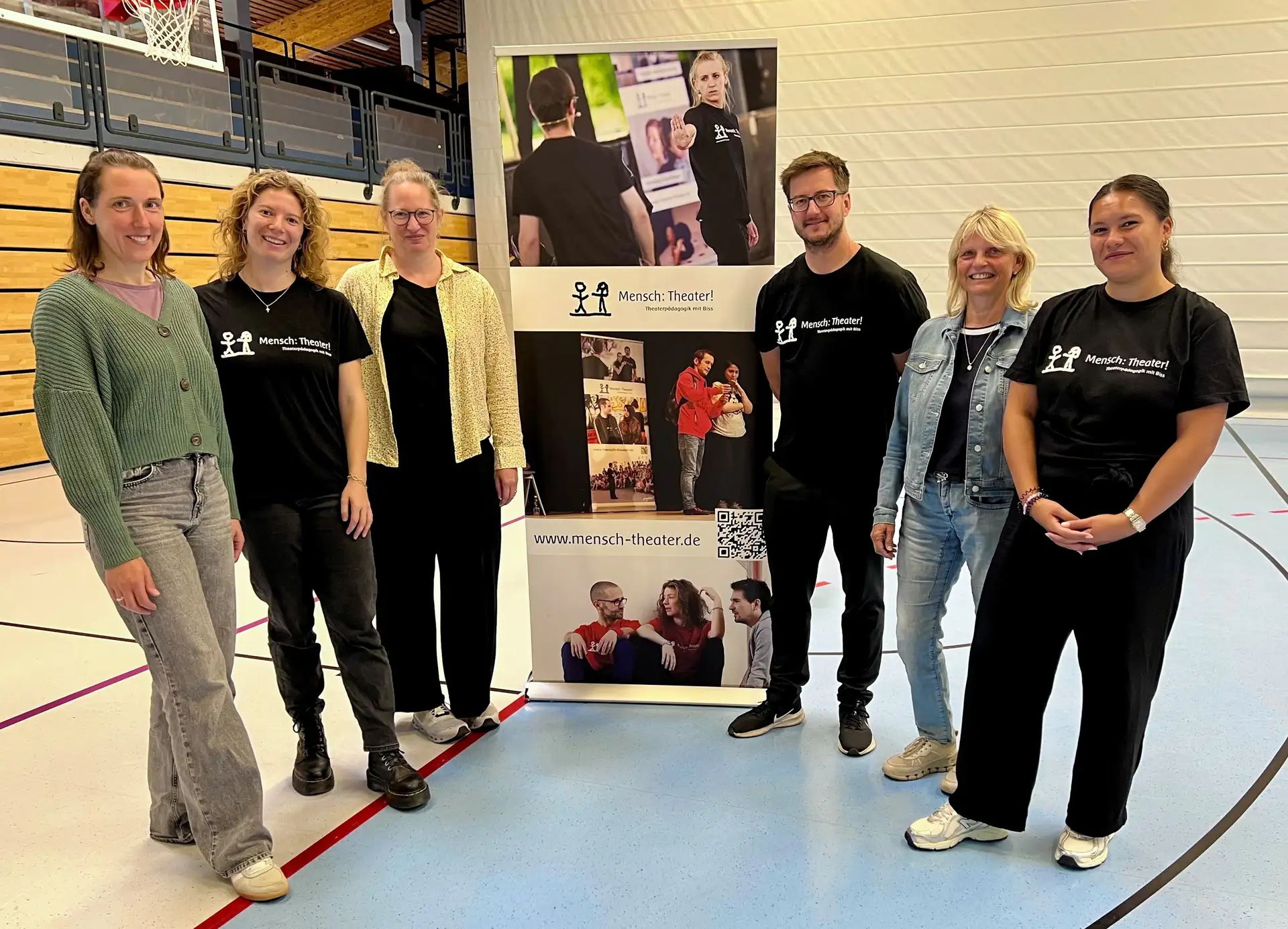 Gruppenfoto mit mehreren Personen (u. a. Mitarbeitende und Theaterpädagogik) vor einem Gebäude.