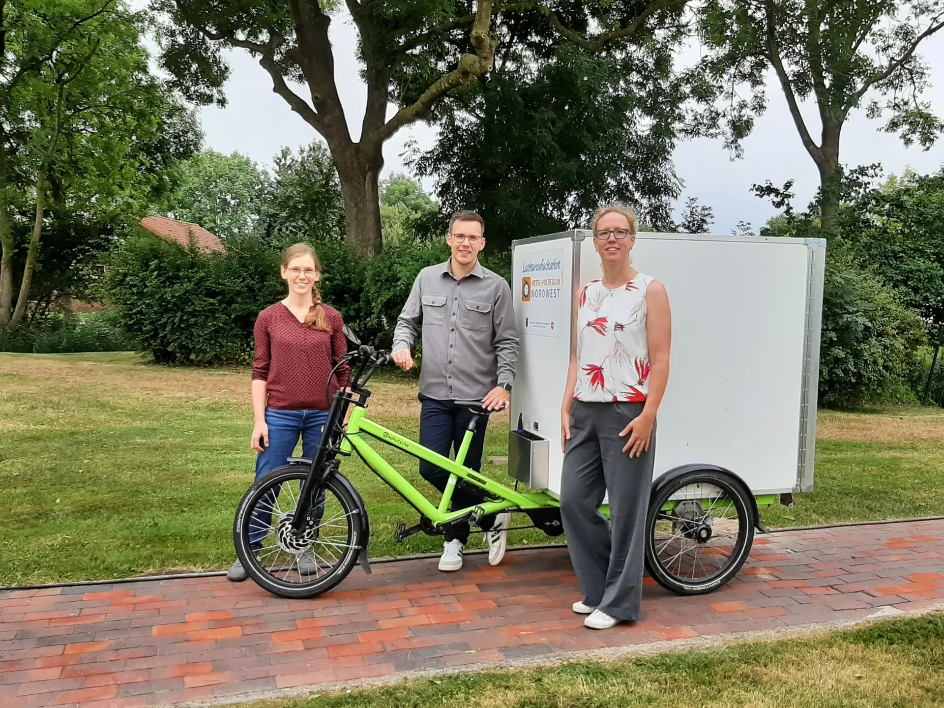 Judith Bremer (Klimaschutzmanagerin Landkreis Wesermarsch), Patrik Poelmeyer (Geschäftsführung Tourismus-Service Butjadingen) und Tina Tönjes (stellvertretende Geschäftsführung Tourismus-Service Butjadingen) bei der Übergabe des E-Schwerlastenrads.