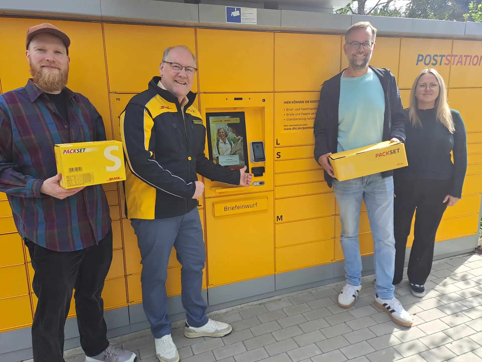 Mehrere Personen stehen vor einer Poststation und sehen sich deren Funktionen an.