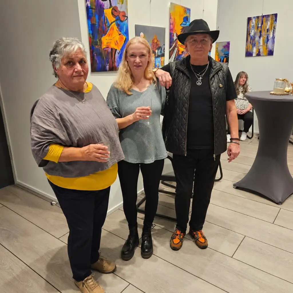Drei Künstlerinnen stehen bei einer Ausstellungseröffnung nebeneinander.