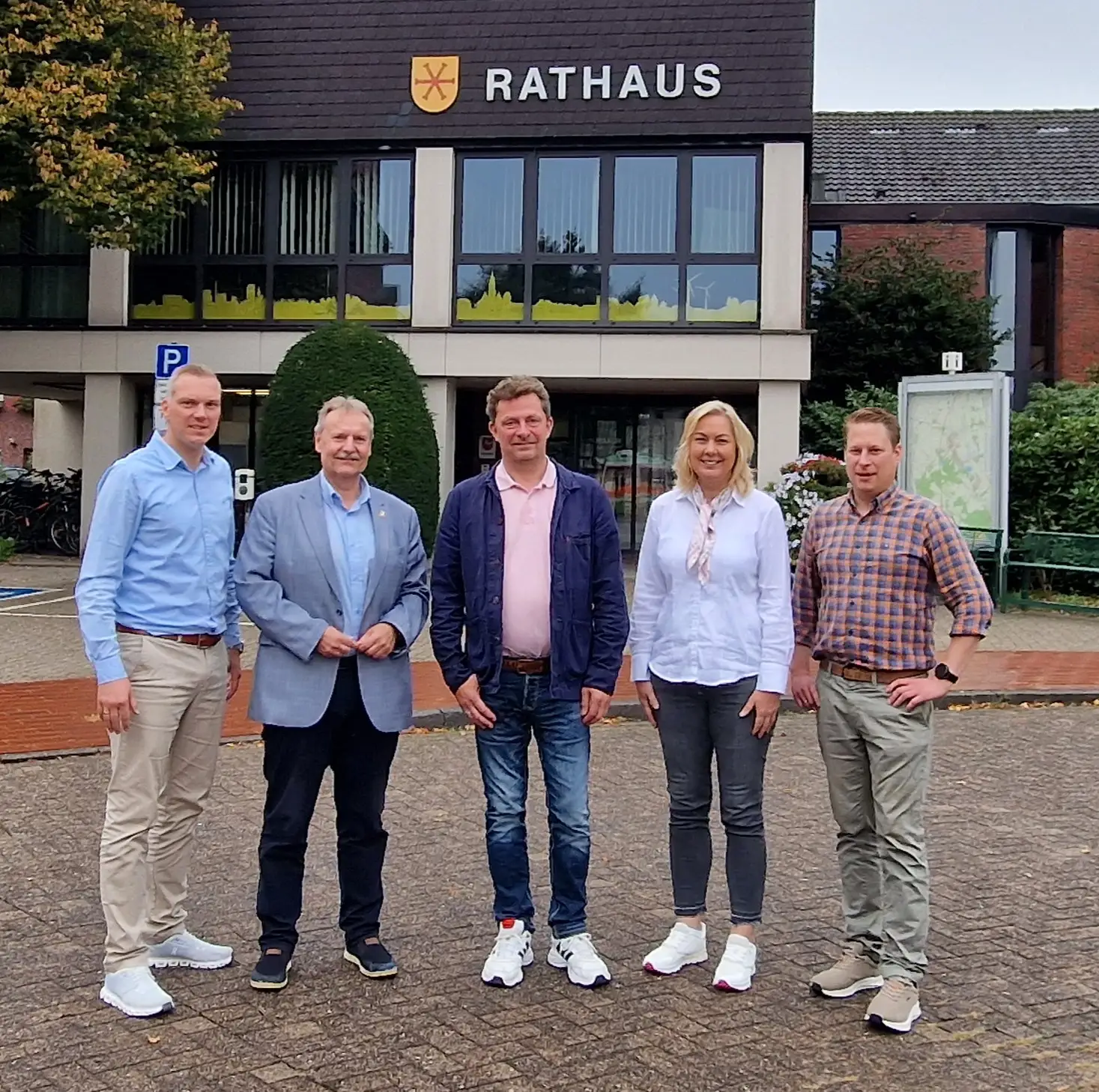 Fünf Personen stehen nebeneinander für ein Gruppenfoto vor dem Rathaus, darunter der Bürgermeister und weitere Mitarbeitende.